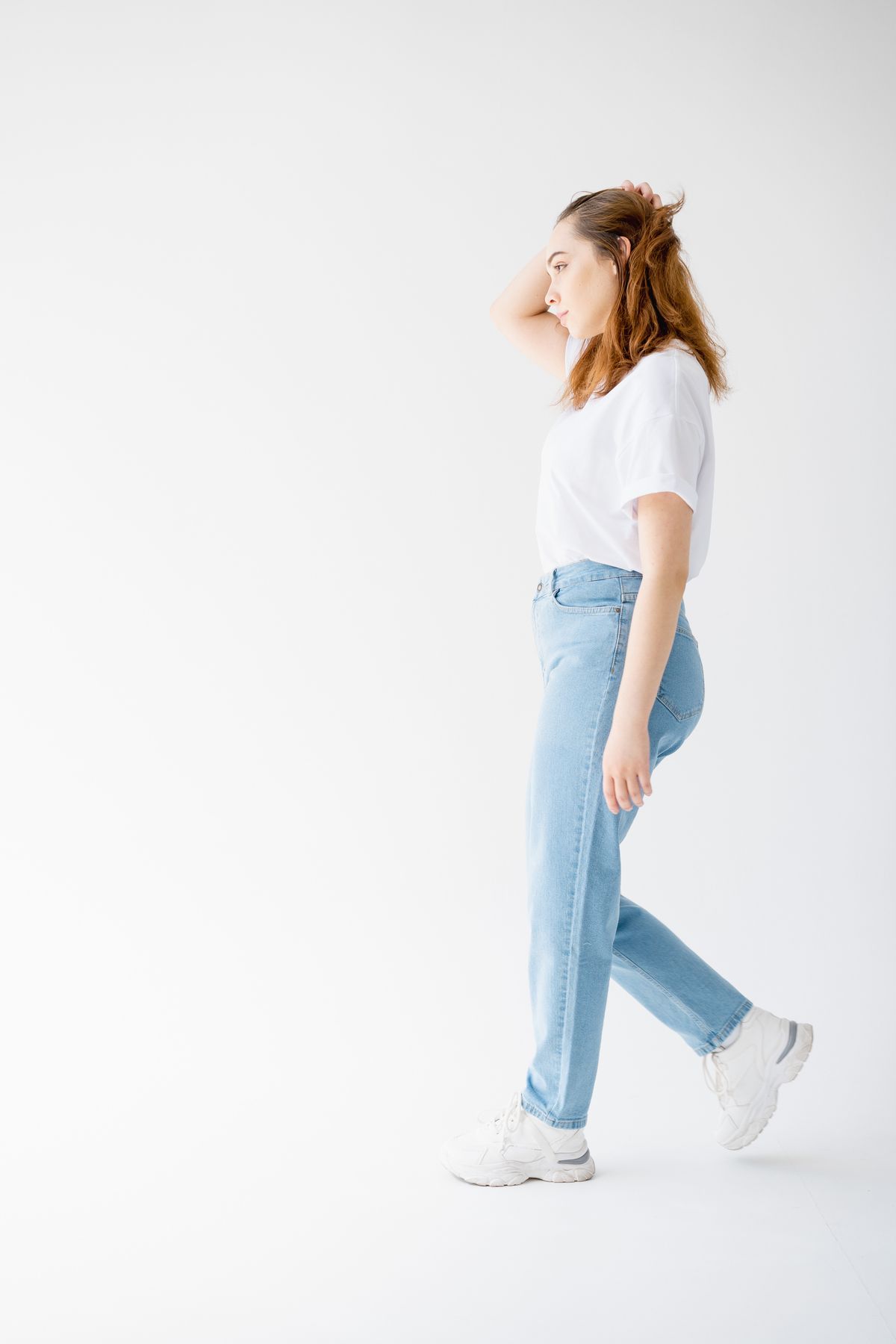 Straight blue jeans and white trainers in a side-on outfit view