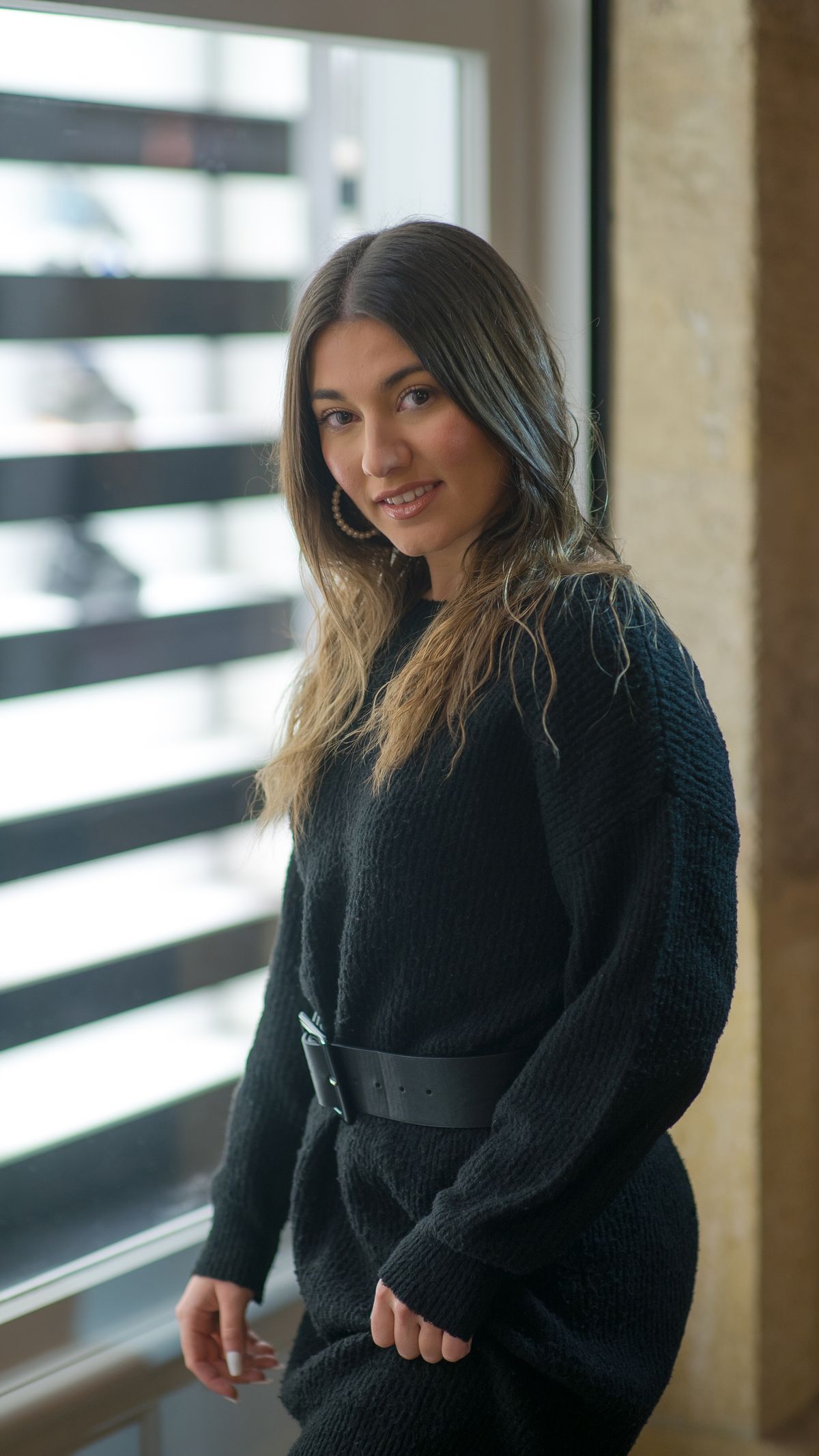 A dark knitted dress with a belt at the waist
