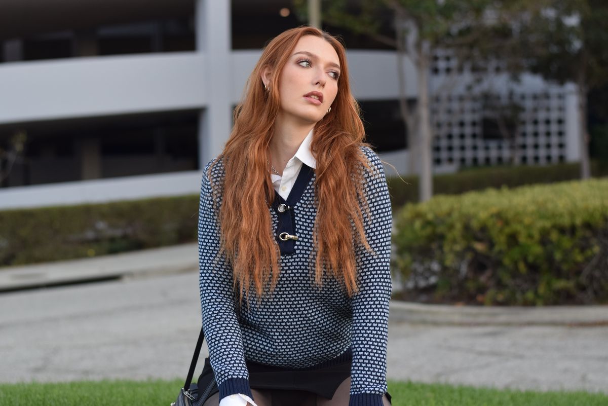 A collared white shirt layered beneath patterned knitwear