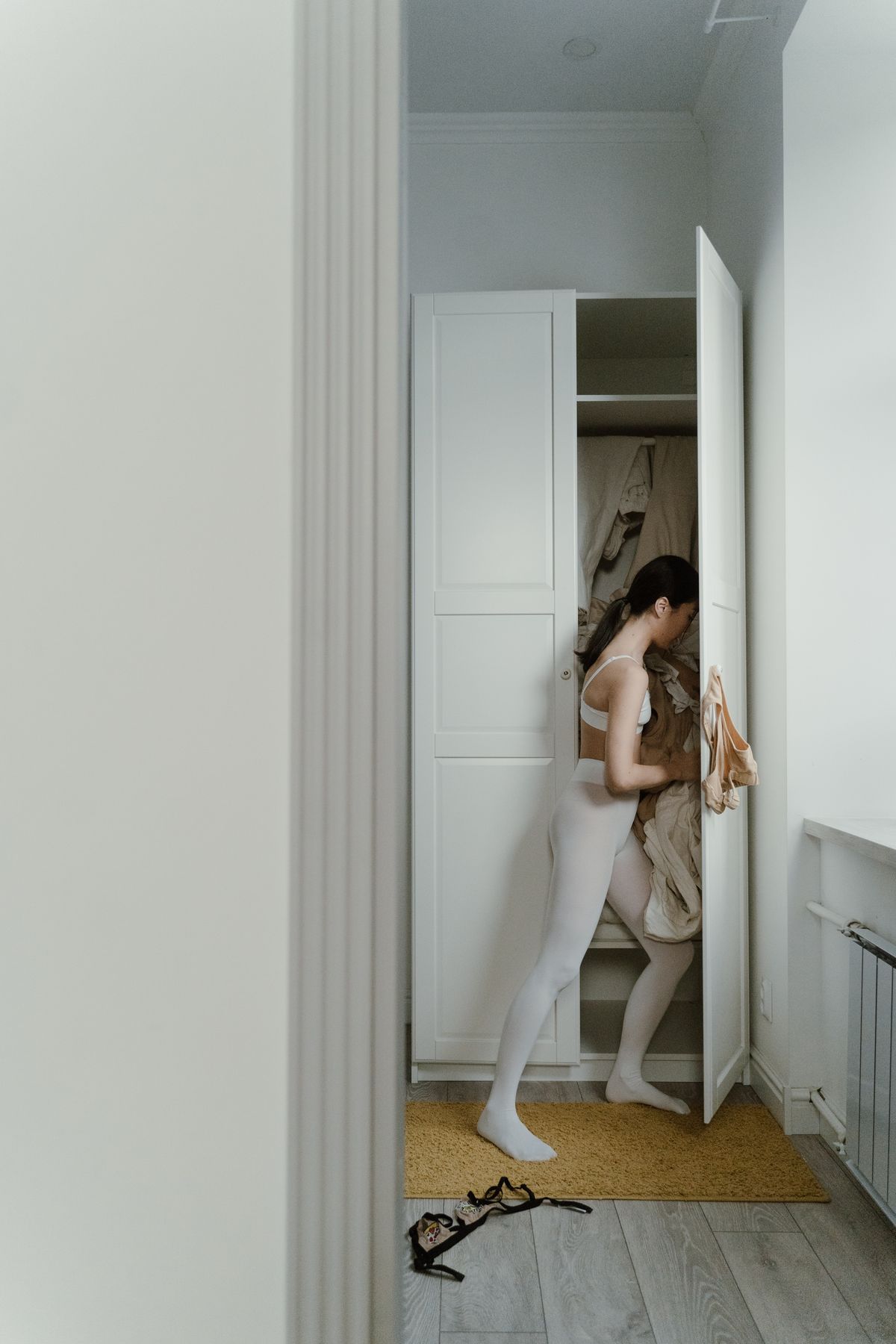 A woman sorting clothes in a small white wardrobe