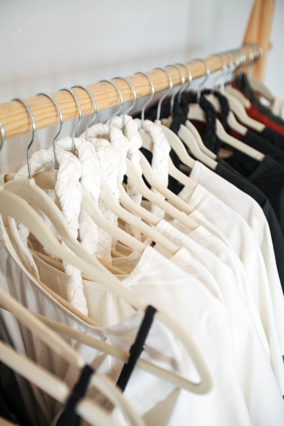 A limited selection of light and dark clothes on a rail