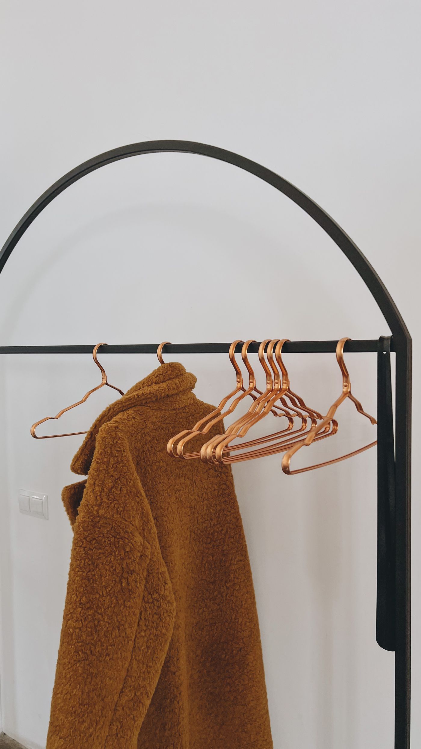 A brown winter coat hanging on a wooden hanger