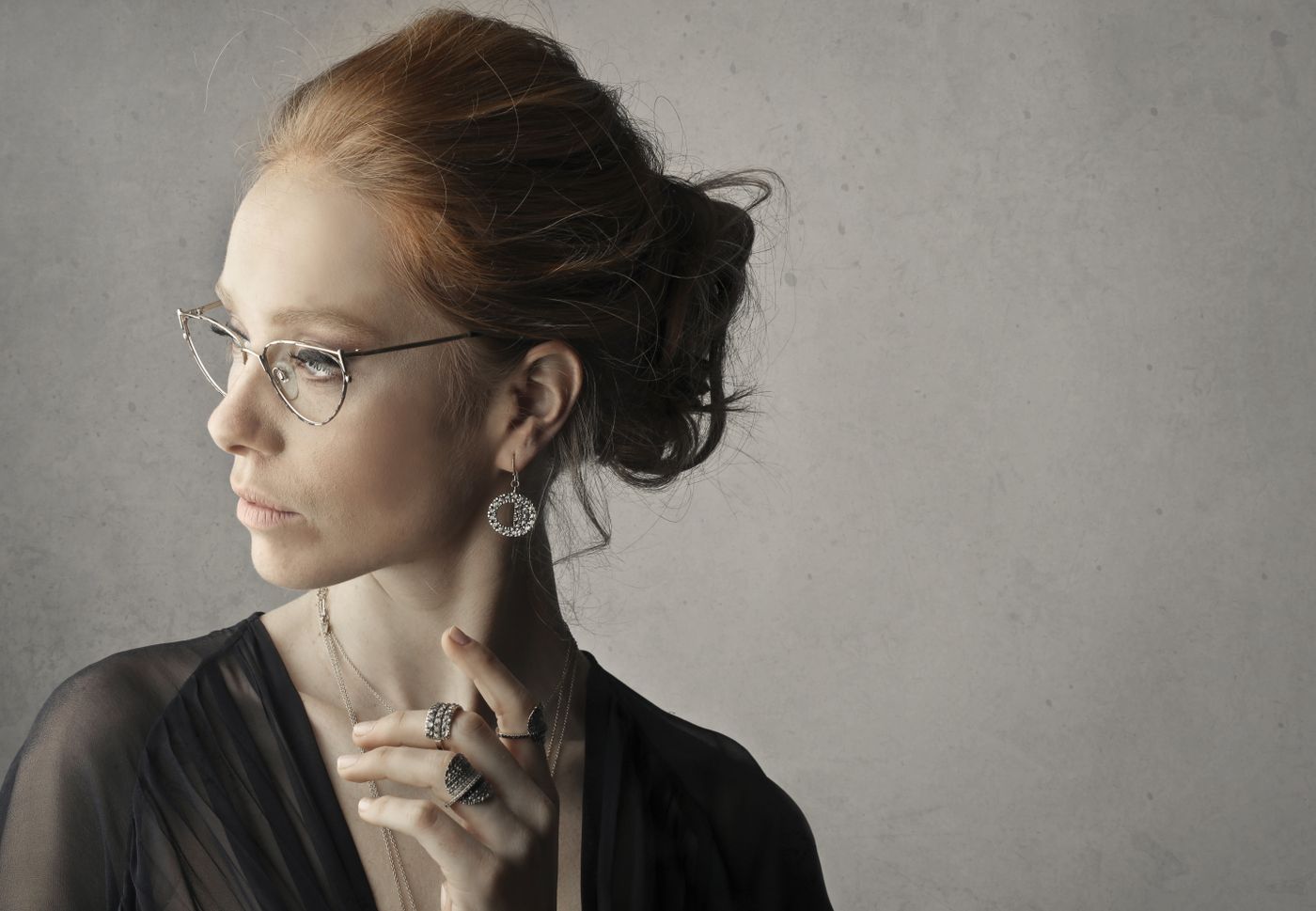 A woman wearing clear glasses and drop earrings