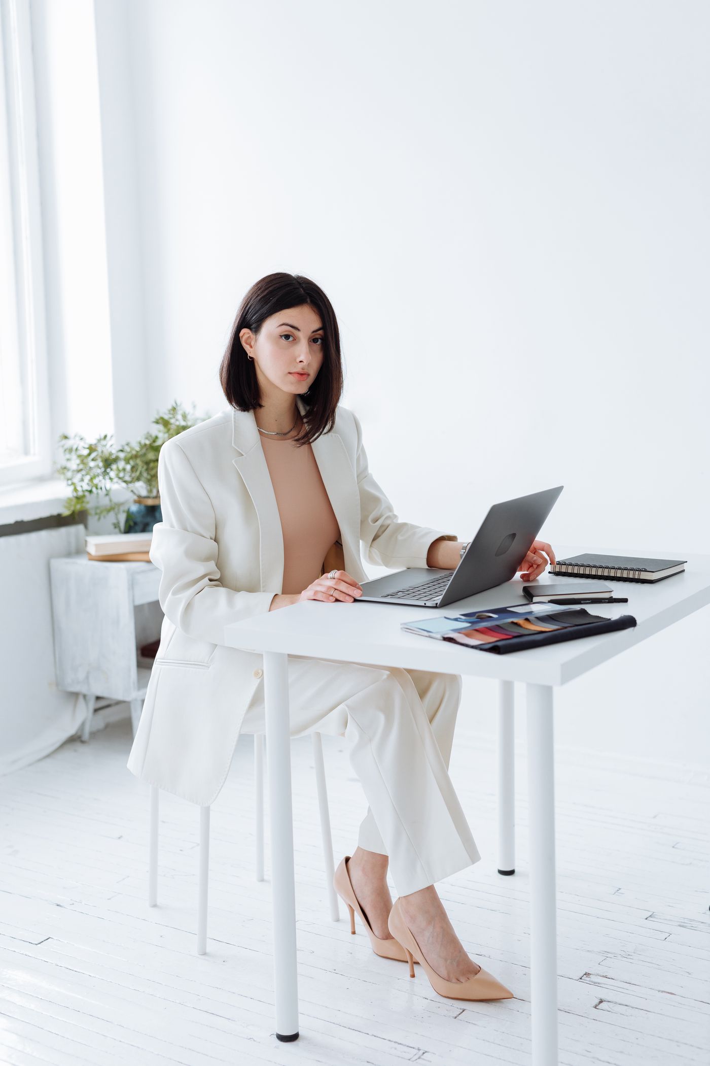 A woman in a light blazer working beside a window