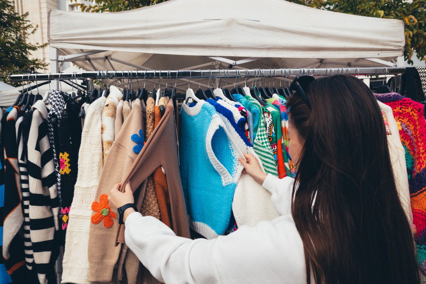 A shopper looking at knitwear at an outdoor clothes stall